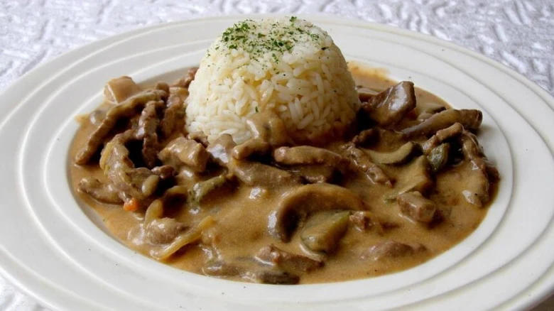 Hotová hovězí stroganov s rýží na talíři.