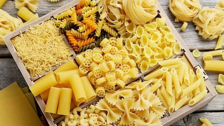 Různé druhy sušených italských těstovin v dřevěném podnose.