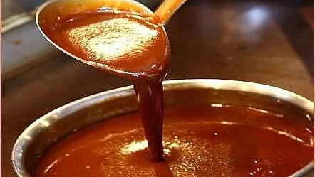 Hustá omáčka Demi Glace se nalévá z lžíce do hrnce.