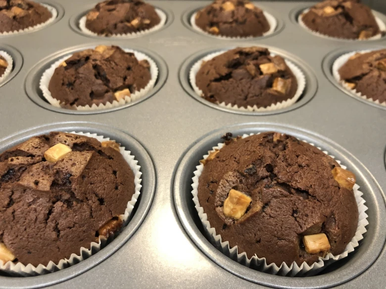 Čokoládové muffiny s kousky čokolády v pekáči.