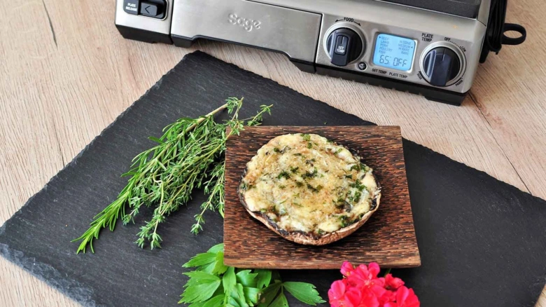 Grillovaný žampion portobello s bylinkami na dřevěném talíři vedle čerstvého tymiánu.