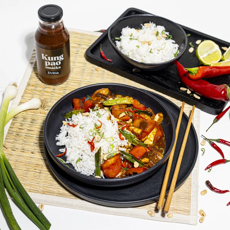 Hotový kuřecí kung pao s rýží, zeleninou a omáčkou v černé misce.