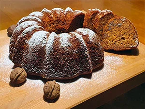 Hotová mrkvová bábovka s ořechy posypaná moučkovým cukrem.