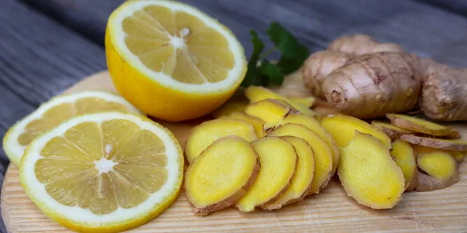 Čerstvé citrony a nakrájený zázvor na dřevěném prknu.
