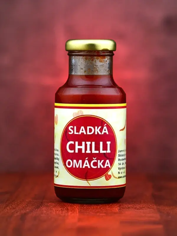 Sklenička sladké chilli omáčky na dřevěném povrchu.