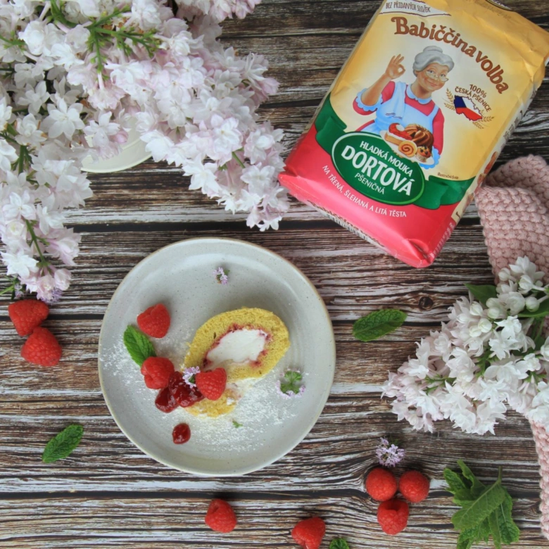 Kousek rolády s mascarpone a malinami na talíři.