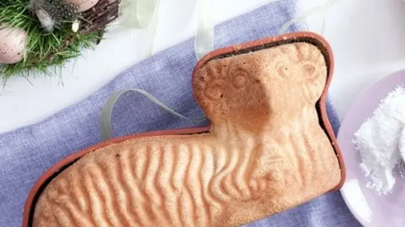 Pečený velikonoční beránek v silikonovém formě na modrém ubrusu.