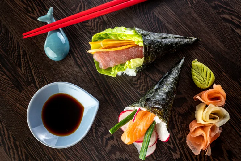 Dva sushi koníky s lososem nebo tuňákem na tmavém dřevěném stole.