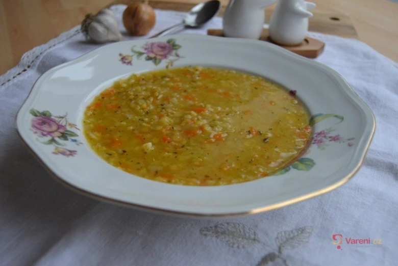 Miska s hotovou čočkovou polévkou se zeleninou na talíři.