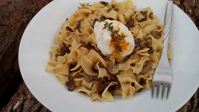 Těstoviny se žampiony a vejcem na bílé talíři.