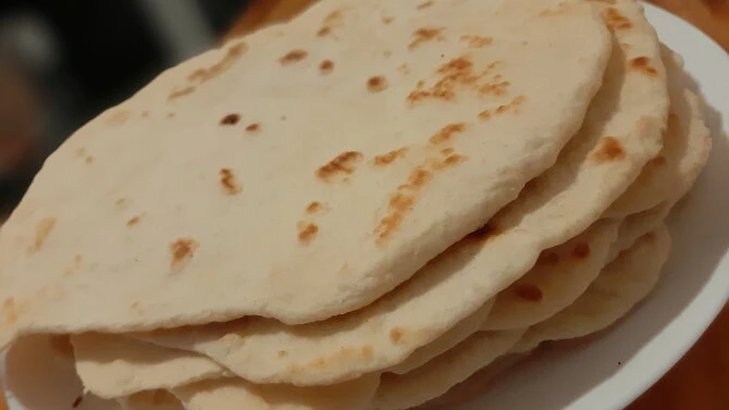 Skládka čerstvých domácích placků z mouky na bílém talíři.