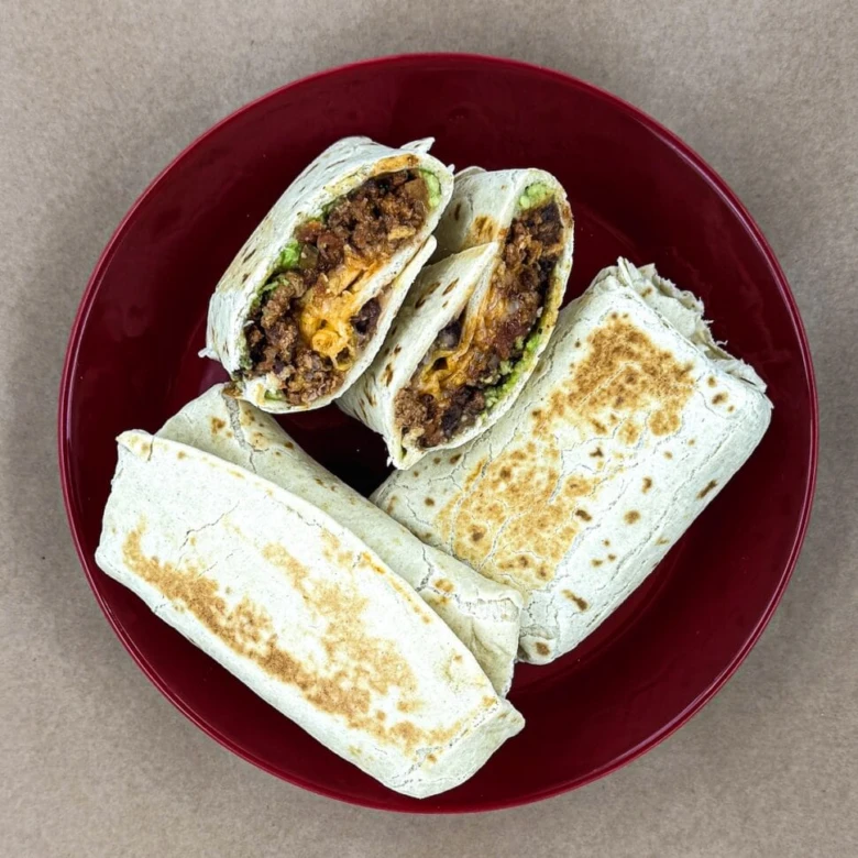 Čtyři kousky burritu s mletým masem na červeném talíři.