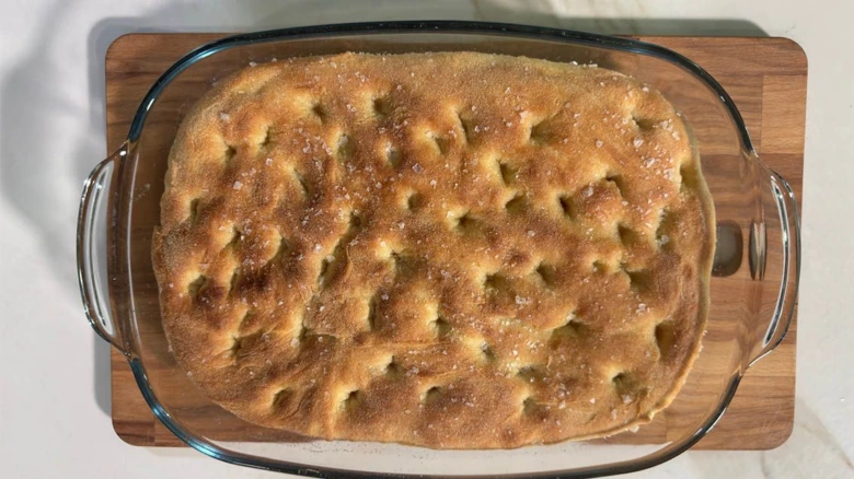 Zlatohnědá pečená focaccia v skleněné mýdlové formě.