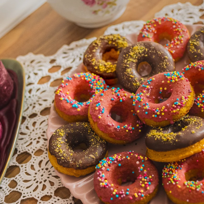 Domácí pečené donuty s čokoládou, růžovou polevou a cukrovými stříkacími.