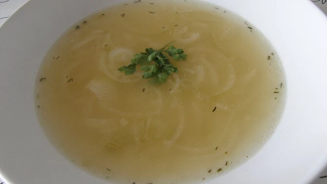 Hot cibulová polévka v bílé misce s petrželkou.