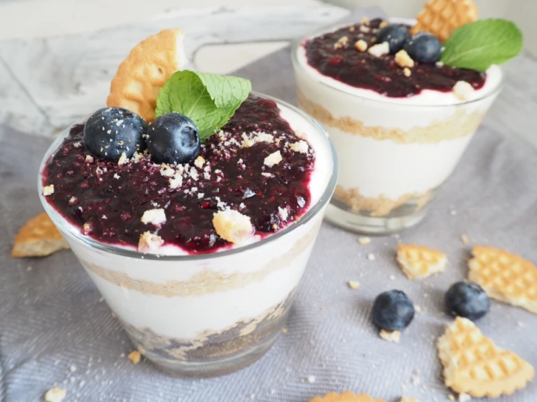 Skleničky s vrstveným cheesecakeem, borůvkami a mátou.