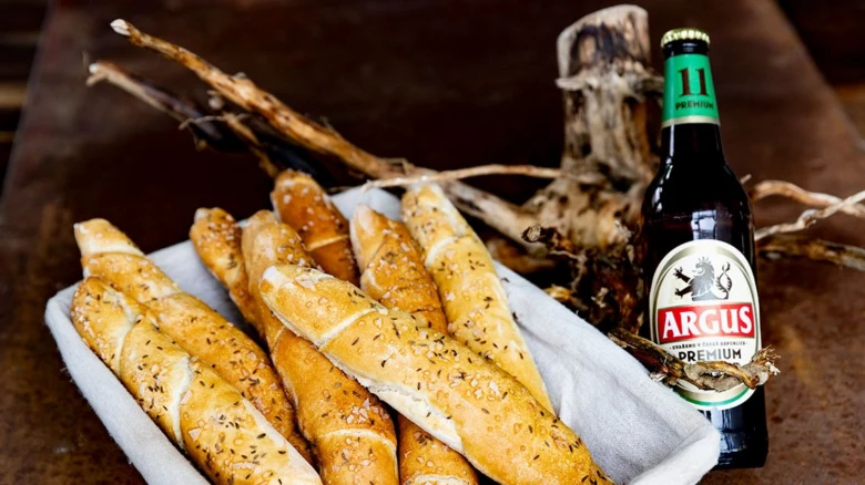 Pivní rohlíky s cibulkou a pivem v košíku na dřevě.