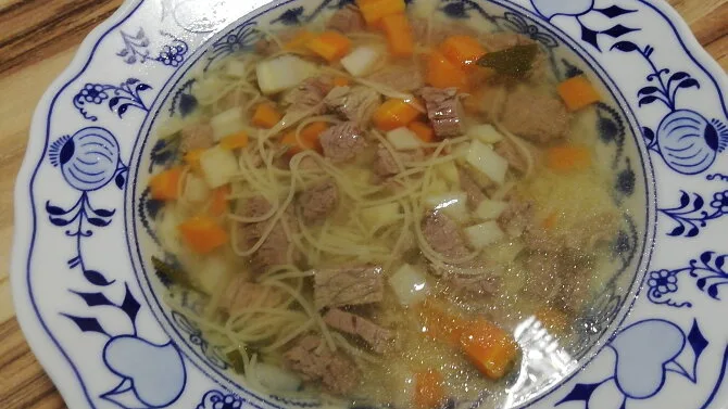 Hotová hovězí vývar s nudlemi a zeleninou v misce.