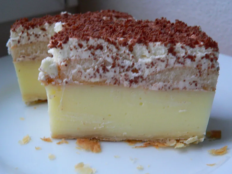 Kousek tiramisu s vrstvami krému a čokoládovou moukou.