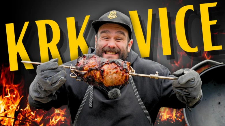 Muž drží na grilu kus krkovice před plameny.