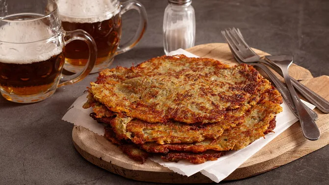 Skládané bramboráky na dřevěném podnosu s pivem.