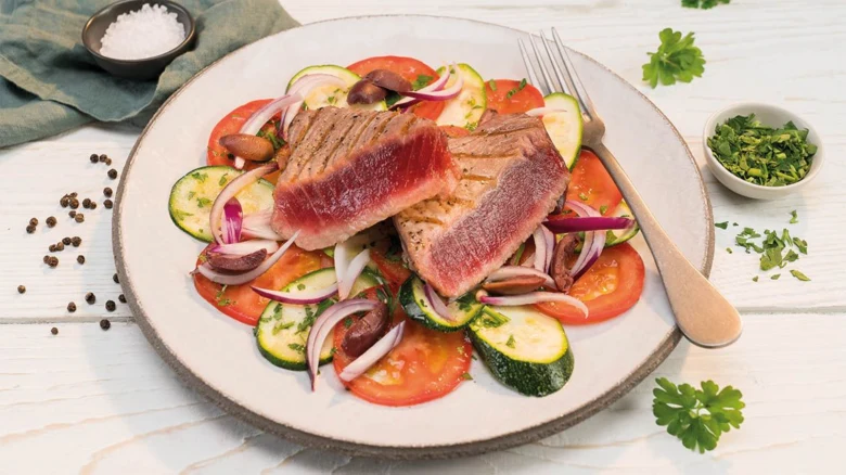 Připravený steak z tuňáka na grilu s čerstvou zeleninou.