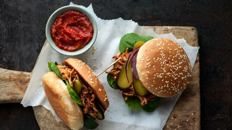 Dva burgery s trhaným vepřovým masem, okurkami, cibulí a omáčkou.