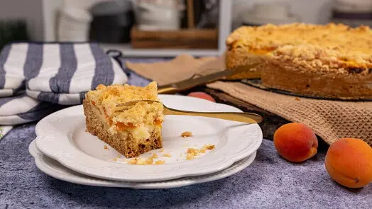 Kousek koláče s ovocem a drobenkou na talíři.