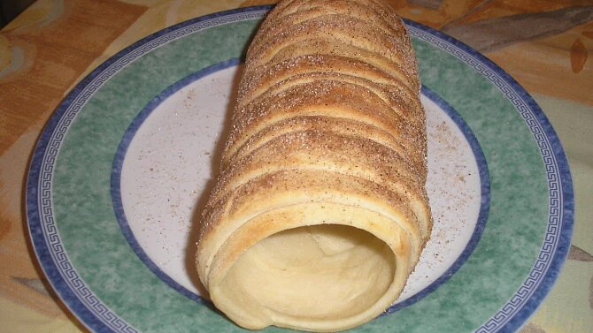 Trdelník s cukrem a skořicí na talíři.