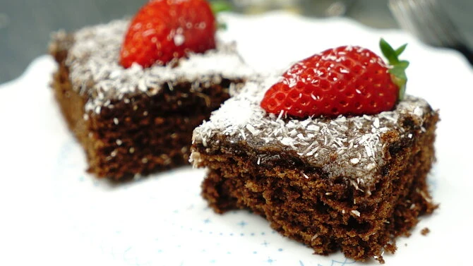 Dvě čokoládové brownie s jahodou a kokosovými vločkami.