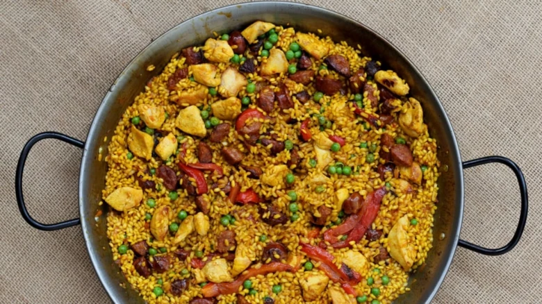 Paella s kuřecím masem v hrnci na lnu.