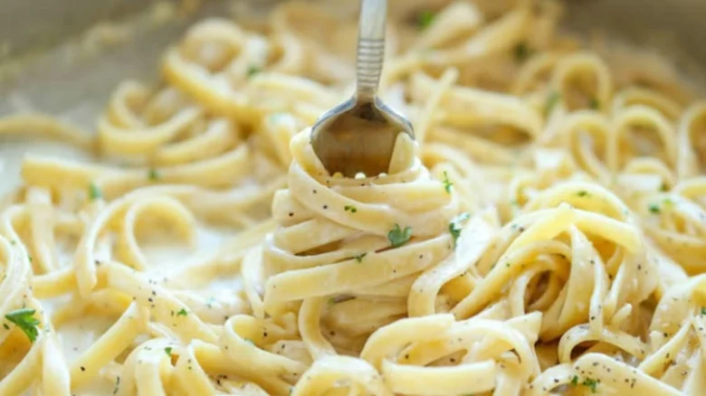 Fork se točí s těstovinami ve smetanové omáčce.