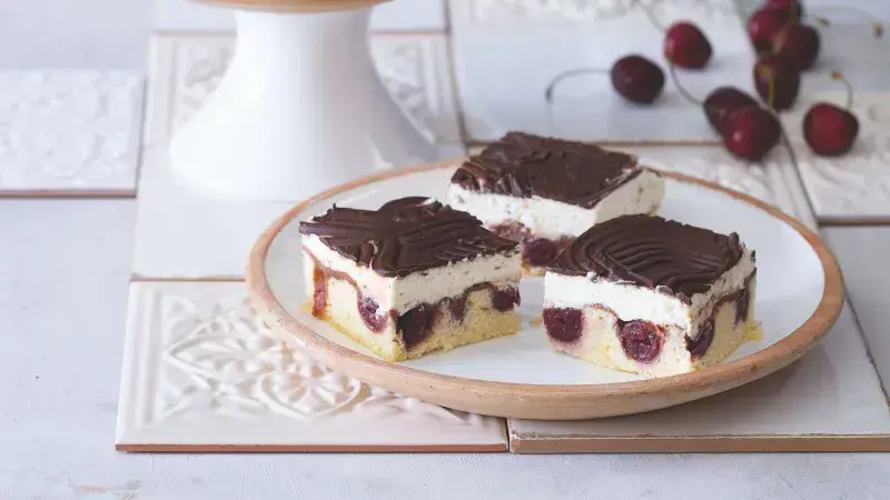Tři čokoládové dezerty s mascarpone, tvarohem a višněmi na talíři.