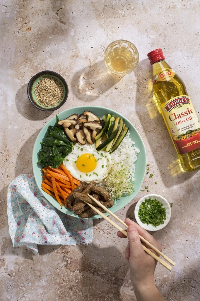 Bibimbap s rýží, vejcem, masem a zeleninou na talíři.
