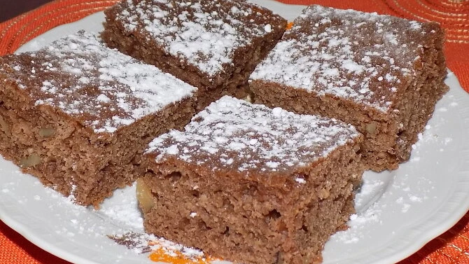 Čtyři čtvercové kousky domácího perníku posypané moučkovým cukrem.