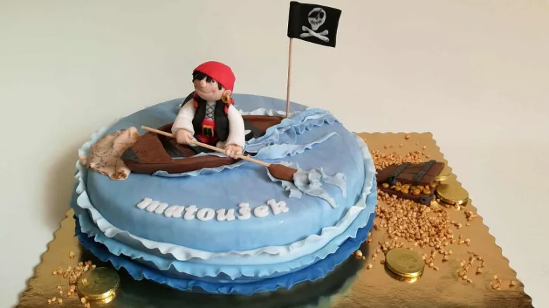 Dětský pirátský dort s postavou chlapce v člunu.