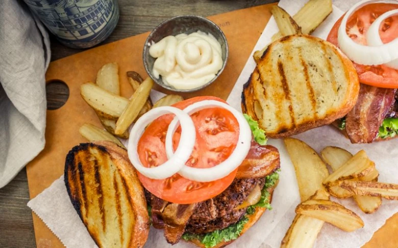 Domácí hovězí hamburgery s bramborami a čerstvými ingrediencemi.