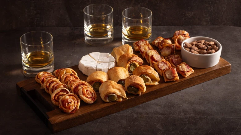 Dřevěná deska s občerstvením, pivo nebo whisky pro oslavu.