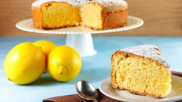 Celá bábovka s citronem, kouskem a čerstvými citrusy.