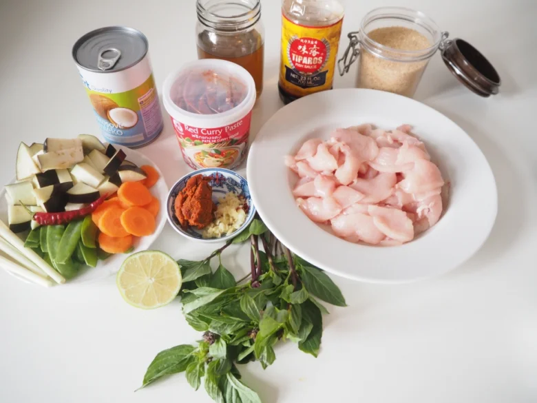 Suroviny pro kari: kuřecí maso, zelenina, červená pastu curry.