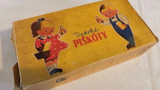 Starý žlutý krabice s dětskými ilustracemi a nápisem Deti Pískoty.