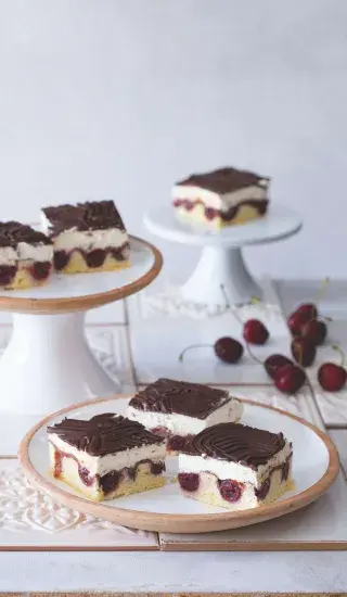 Čtyři čokoládové dezerty s malinami, tvarohem a mascarpone na talířích.