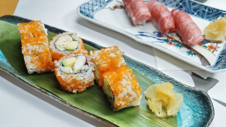 Sushi rolí s kousky zlaté chřipky na zeleném listu.