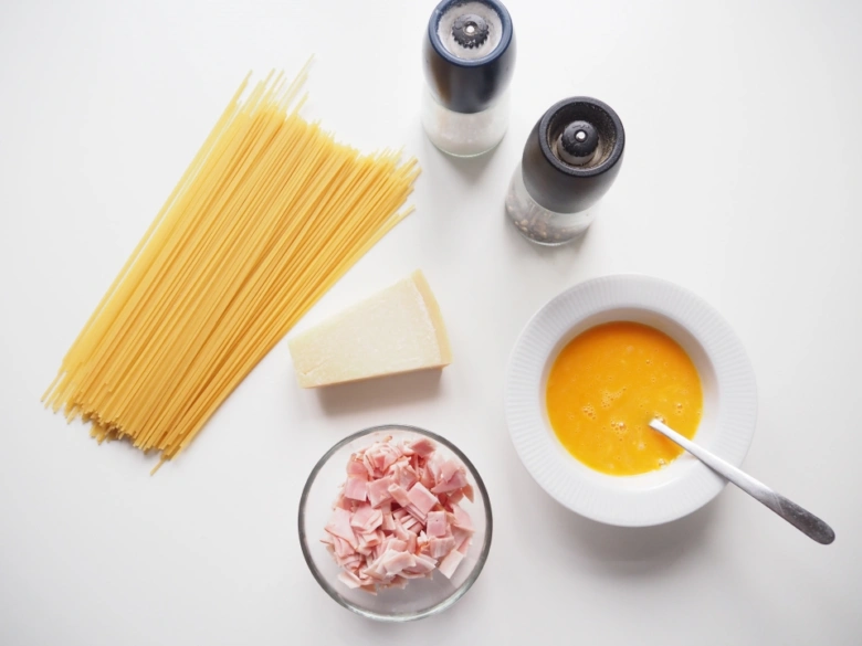 Suroviny na špagety Carbonara: těsto, vejce, sýr, uzená klobása.