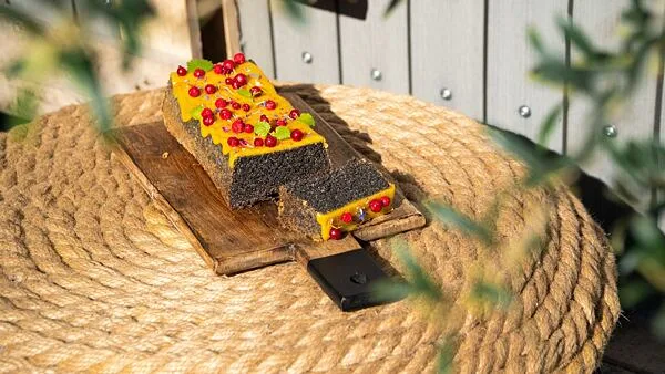 Makový koláč s citronovou polevou na dřevěném podstavci.