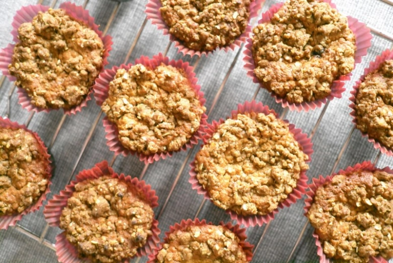Svěžě upečené ovesné muffiny v růžových papírových formách na mřížce.