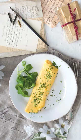 Hotová vaječná omeleta s bylinkami na talíři.