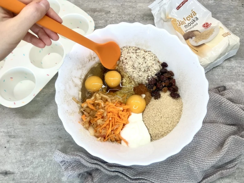 Míchání surovin pro bezlepkové muffiny v míse s vejci a mrkví.