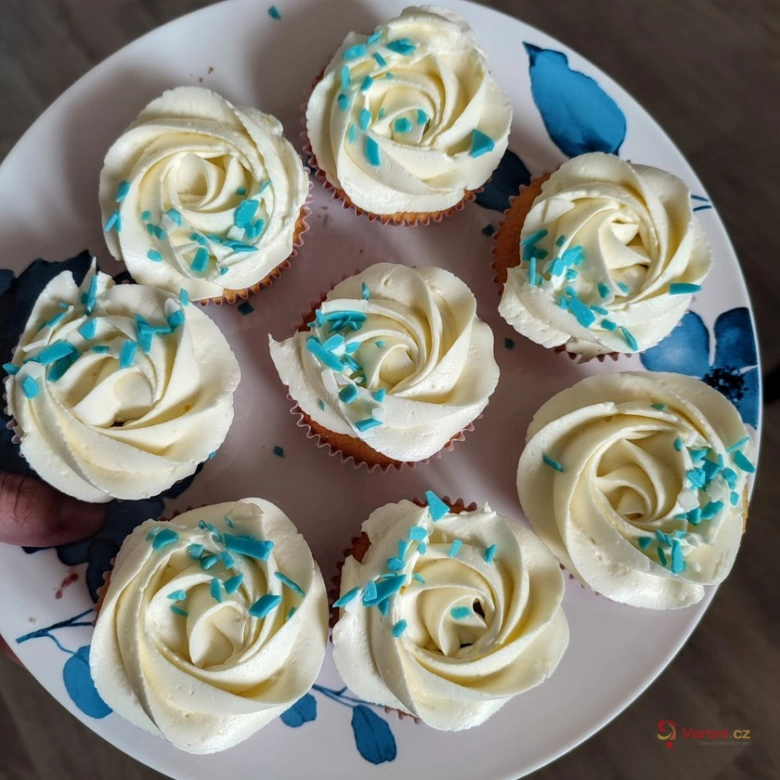 Deset šlehaných muffinů s modrými posypem na talíři.