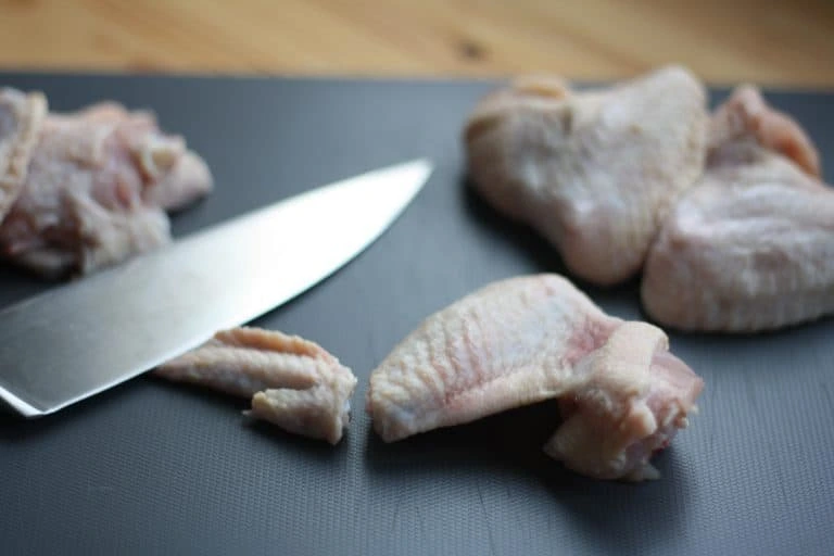 Raw chicken wings on cutting board with knife